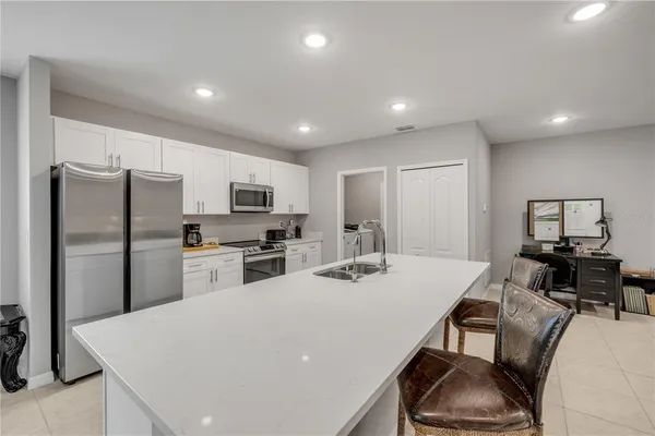 a kitchen with stainless steel appliances a dining table chairs stove refrigerator and cabinets