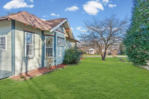 a view of a house with a big yard and large trees