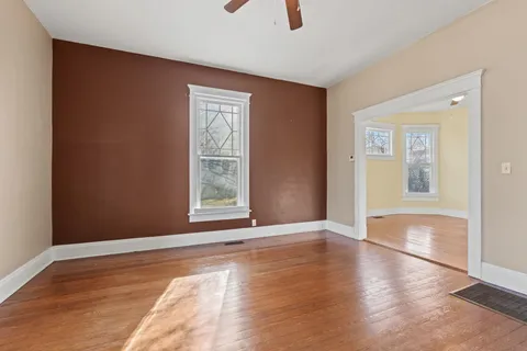 a view of an empty room with window and wooden floor
