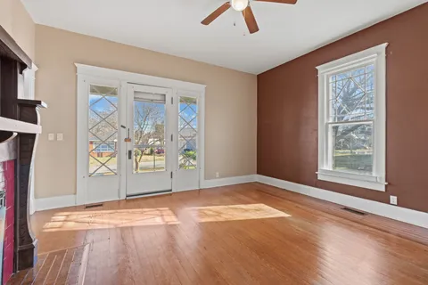a view of an empty room with window and wooden floor