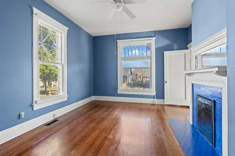 a view of an empty room with a window and wooden floor