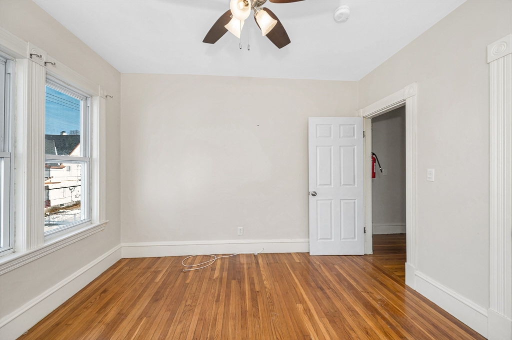 85 Sherman Street, Unit 3 Lowell, MA 01852 - Photo 3 of 11 a view of an empty room with wooden floor and window