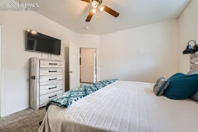 a bedroom with a bed a flat screen tv and a chandelier