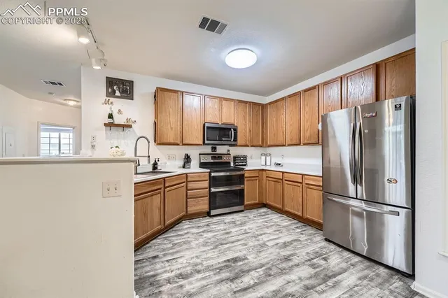 a kitchen with granite countertop stainless steel appliances a refrigerator sink microwave and cabinets