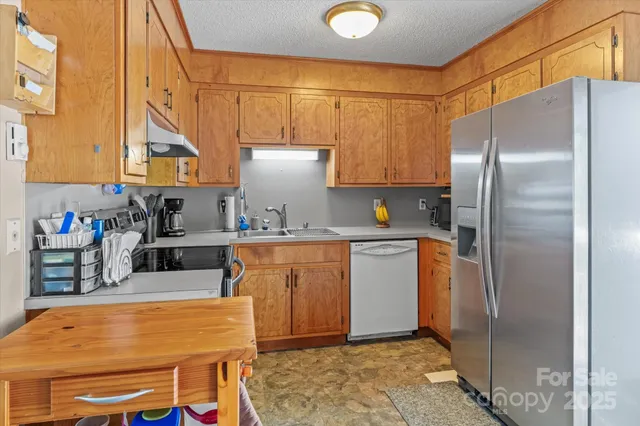 a kitchen with stainless steel appliances granite countertop a refrigerator a sink a stove and white cabinets