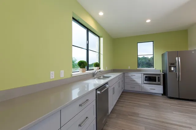 a large kitchen with stainless steel appliances a large window and a counter top space