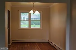 an empty room with wooden floor chandelier and window