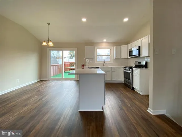 a kitchen with stainless steel appliances granite countertop a stove top oven a sink dishwasher and a refrigerator with wooden floor