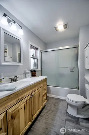 a bathroom with a granite countertop sink a toilet a mirror and shower