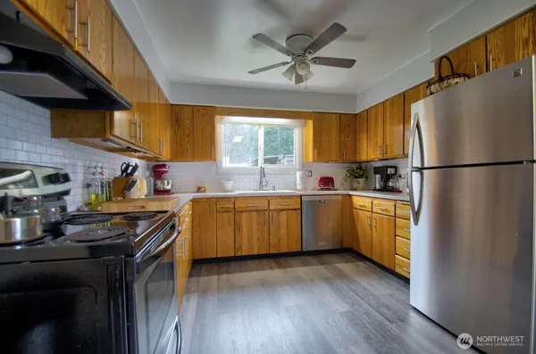 a kitchen with a refrigerator a sink dishwasher stove and wooden cabinets