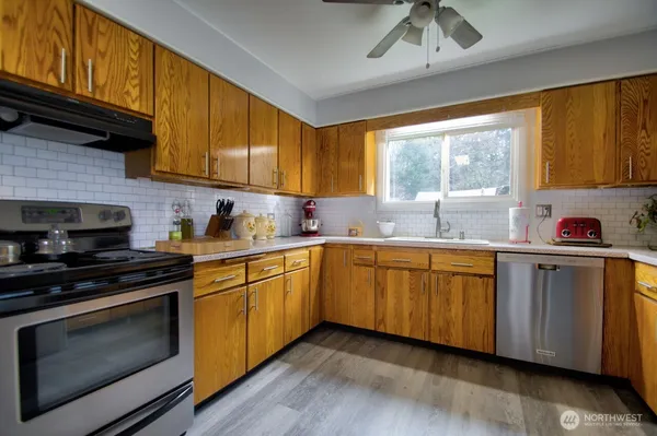 a kitchen with granite countertop wooden floors white cabinets sink and a window