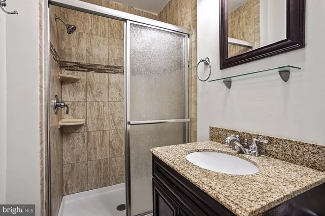a bathroom with a granite countertop shower sink and mirror