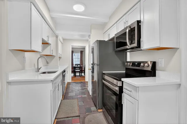 a kitchen with stainless steel appliances a sink a stove a microwave a sink a refrigerator and cabinets