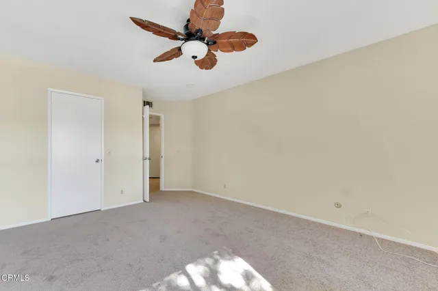 an empty room with a ceiling fan and carpet
