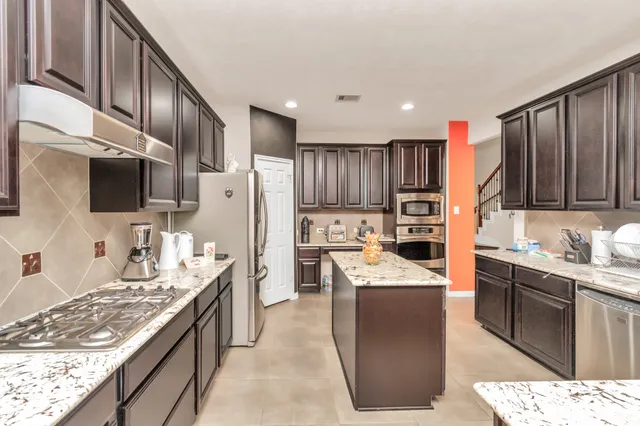 a kitchen with stainless steel appliances granite countertop a refrigerator stove and oven
