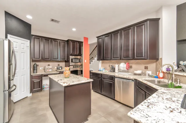 a kitchen with stainless steel appliances granite countertop a sink dishwasher stove refrigerator and cabinets
