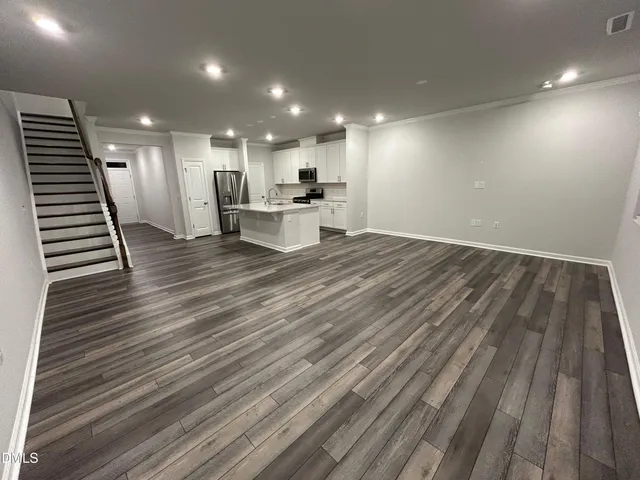 a kitchen with kitchen island a counter top space a refrigerator a sink and cabinets