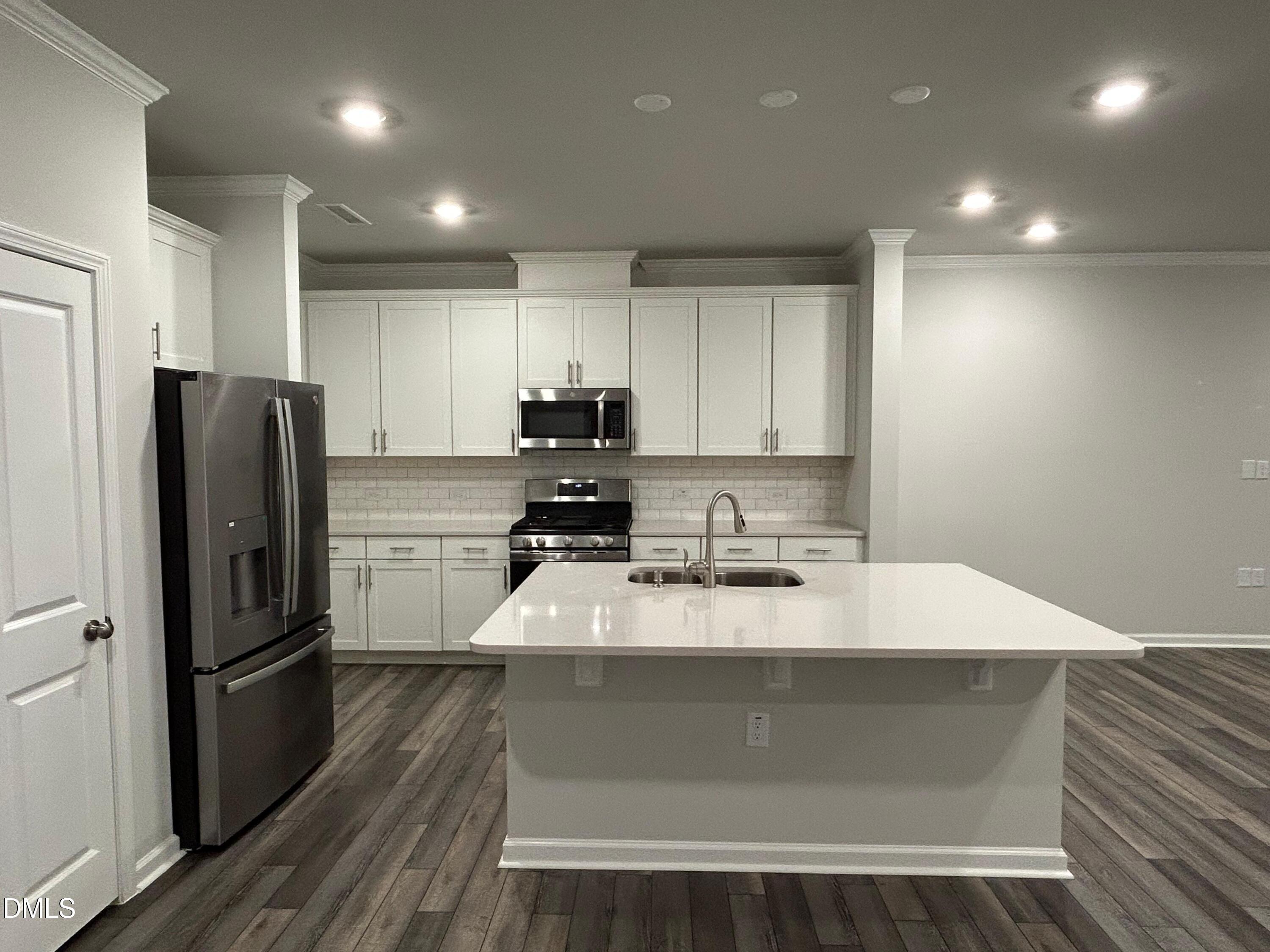113 Vanilla Orchid Lane Garner, NC 27529 - Photo 14 of 32 a kitchen with kitchen island a counter top space a refrigerator a sink and cabinets