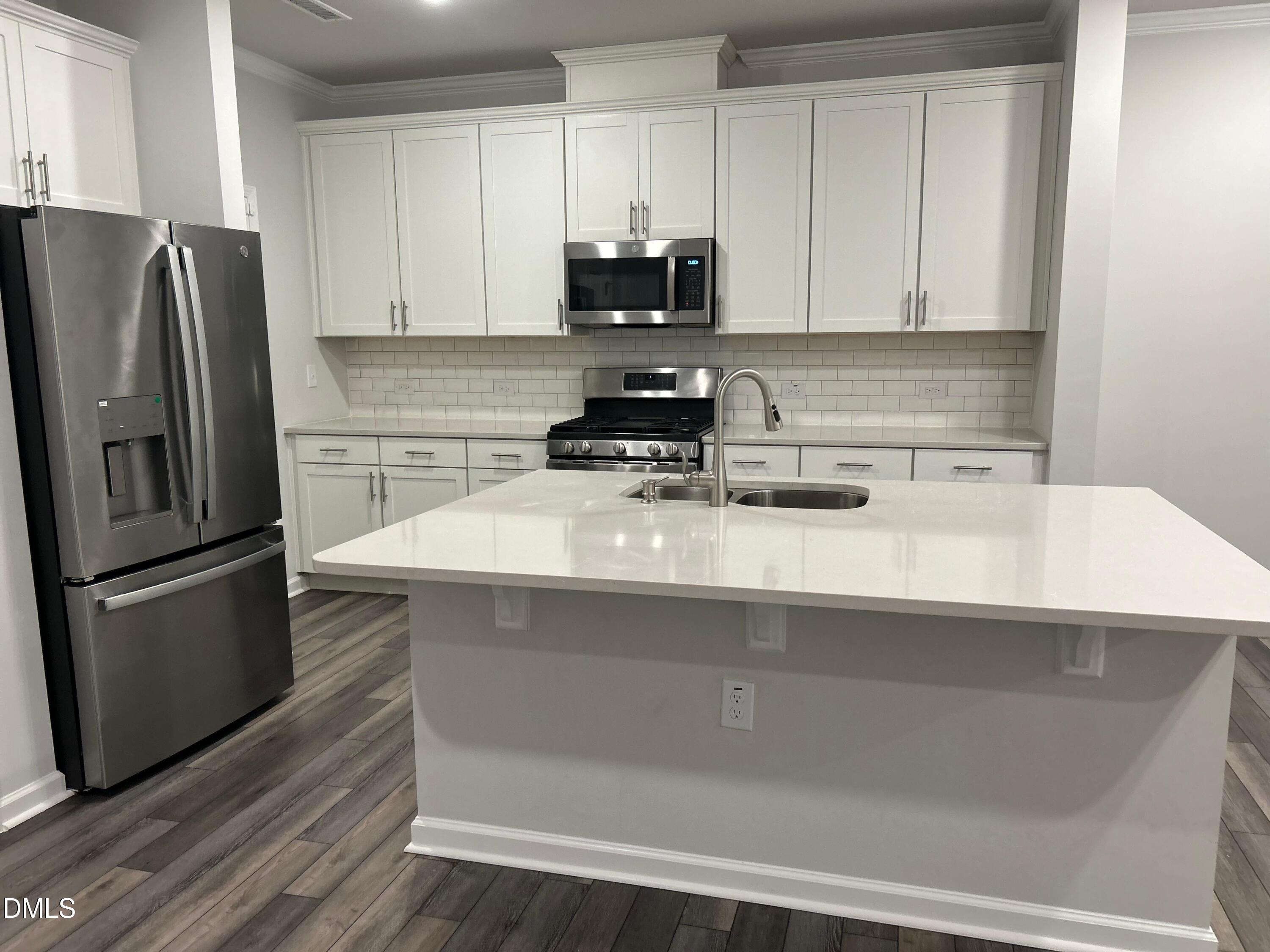 113 Vanilla Orchid Lane Garner, NC 27529 - Photo 17 of 32 a kitchen with a sink a refrigerator and cabinets