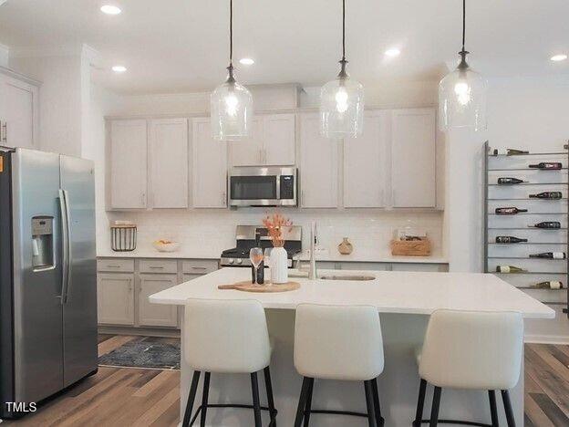 113 Vanilla Orchid Lane Garner, NC 27529 - Photo 3 of 32 a kitchen with stainless steel appliances a dining table chairs refrigerator and microwave