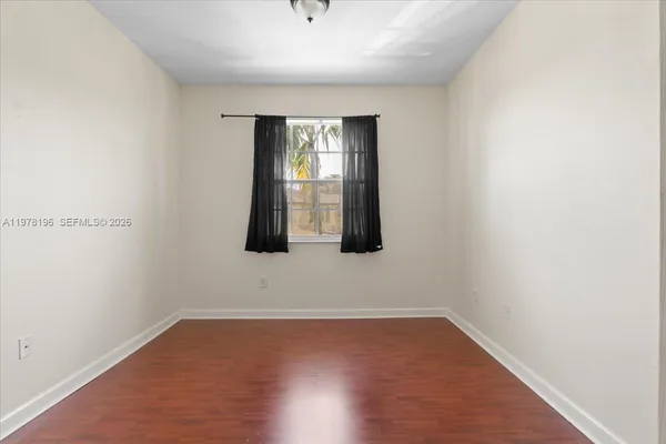 a view of an empty room with wooden floor and windows
