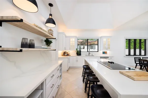 a kitchen with stainless steel appliances a stove a sink a oven a dining table and chairs with white cabinets