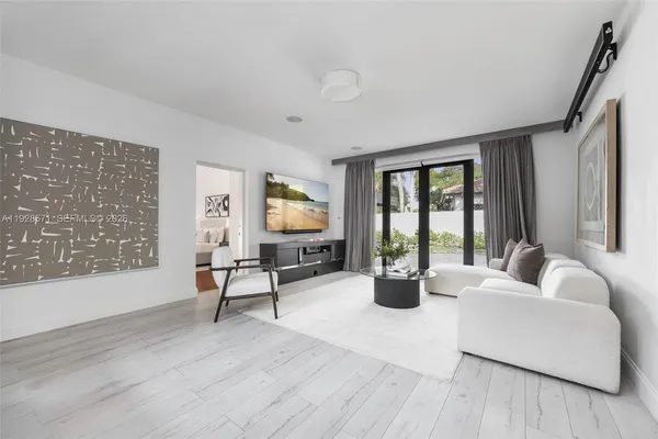 a living room with furniture large window and wooden floor