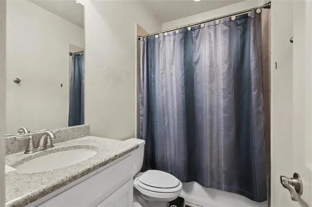a bathroom with a granite countertop sink toilet and a mirror