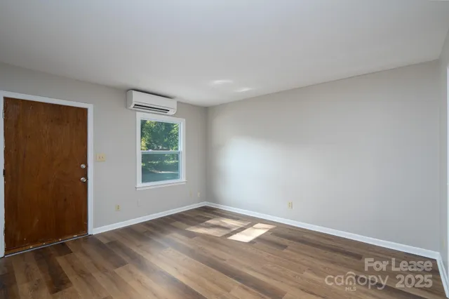 an empty room with wooden floor and window