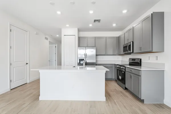 a large kitchen with stainless steel appliances granite countertop a stove top oven a sink and white cabinets