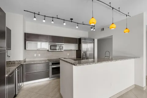 a kitchen with stainless steel appliances granite countertop a sink a stove and a refrigerator