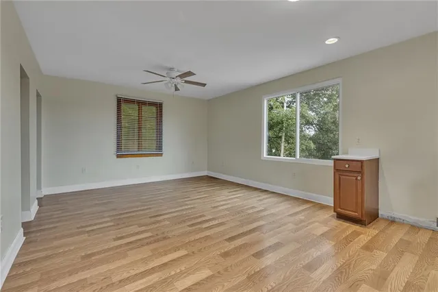 a view of an empty room with a window and wooden floor