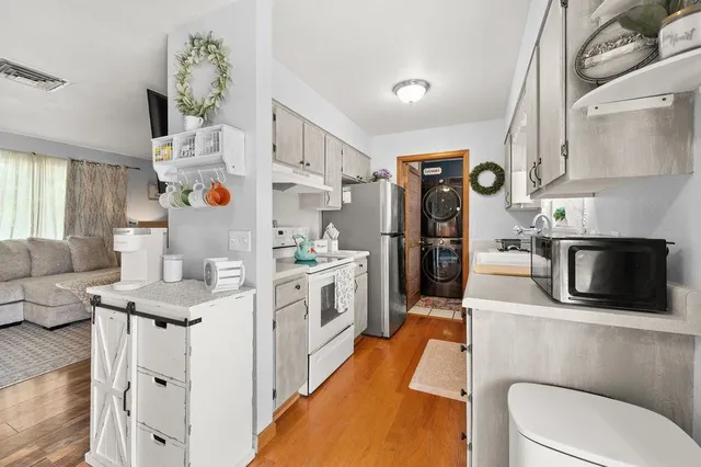 a kitchen with stainless steel appliances kitchen island granite countertop a refrigerator a stove and white cabinets with wooden floor