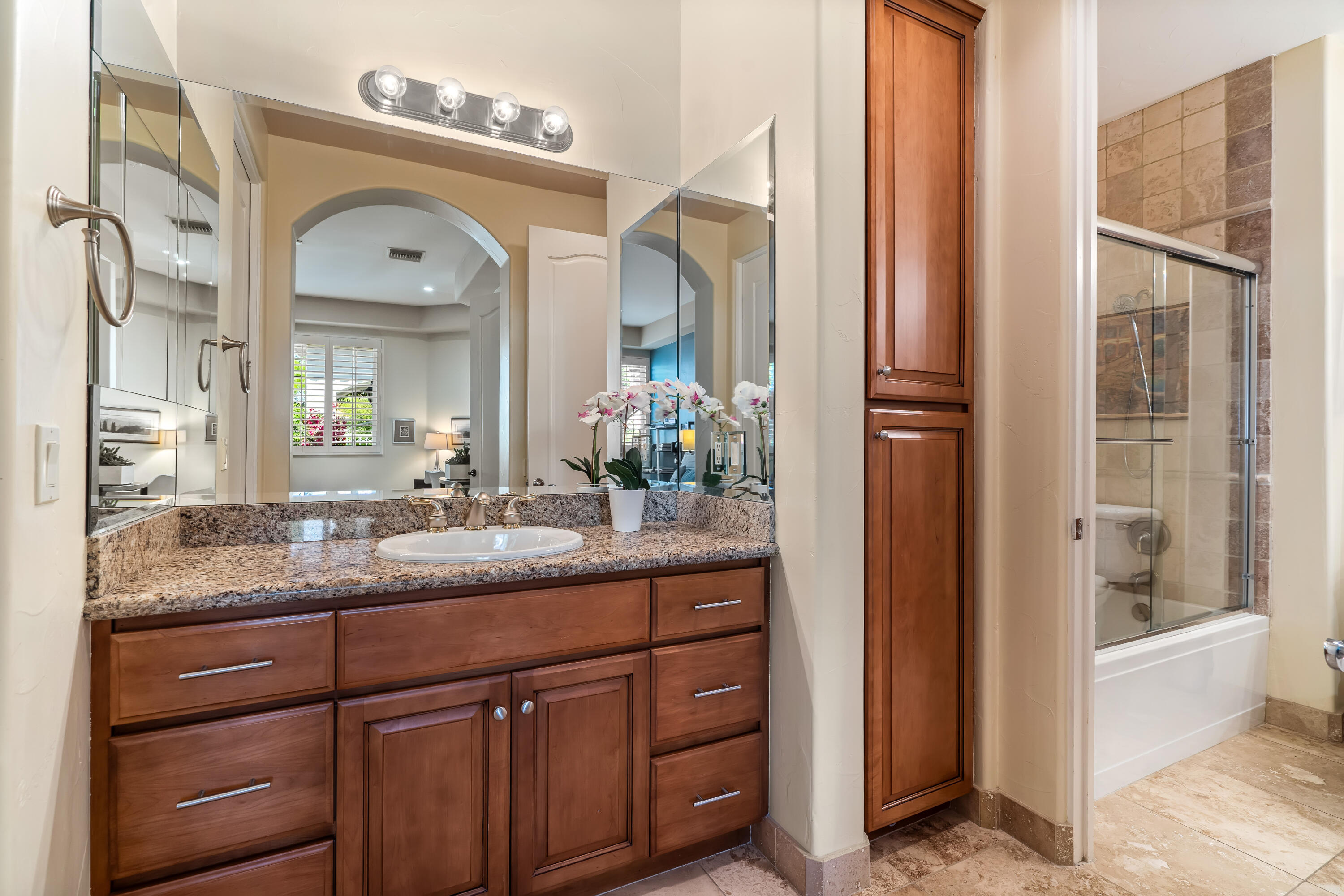 106 Piazza Perrone Palm Desert, CA 92260 - Photo 45 of 68 a bathroom with a granite countertop sink vanity mirror next to a living room