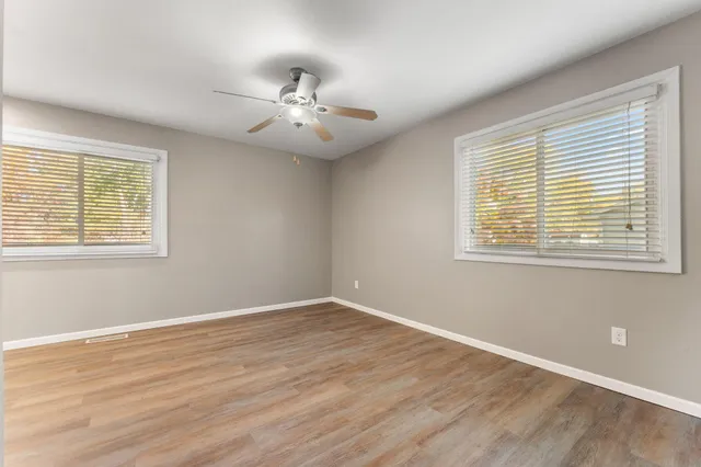 a view of an empty room with wooden floor and a window