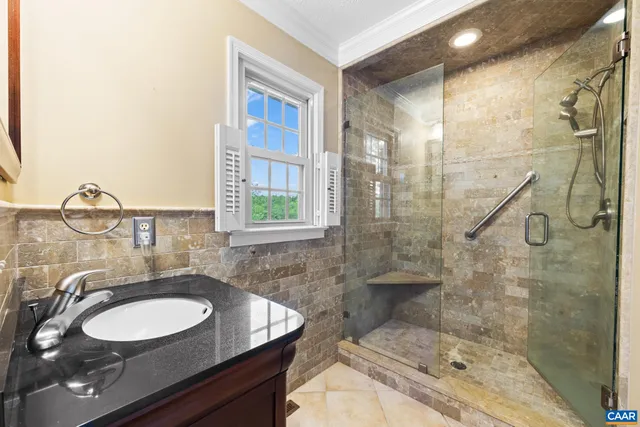 a bathroom with a granite countertop sink a toilet a mirror and shower