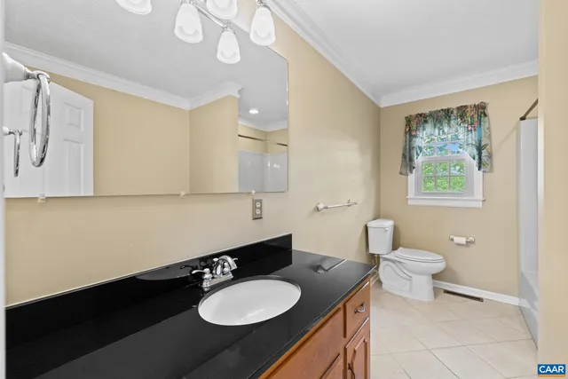 a bathroom with a granite countertop sink a toilet a mirror and a window