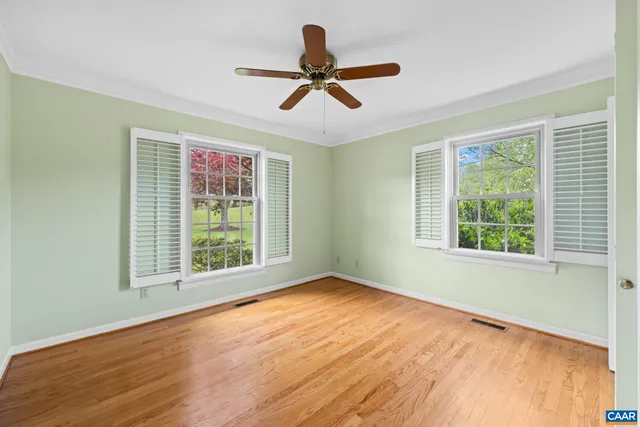 a view of empty room with wooden floor and fan