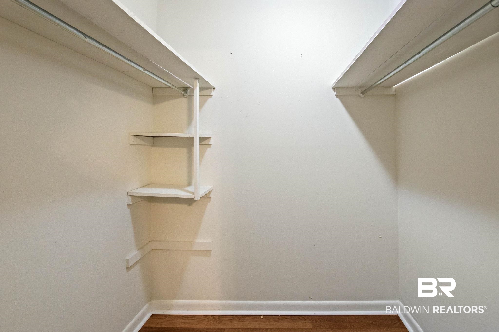 384 Old Bratt Road Atmore, AL 36502 - Photo 38 of 64 Walk-in closet featuring wood-finish flooring, white baseboards, white walls, built-in shelving, and dual clothing rods