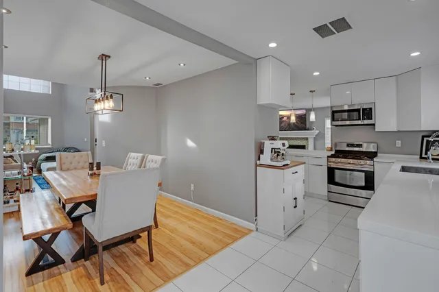 a kitchen with stainless steel appliances kitchen island granite countertop a sink dishwasher a stove a refrigerator and a dining table with wooden floor