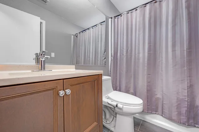 a bathroom with a sink a toilet a mirror and shower curtain