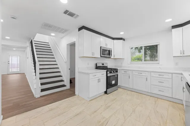 a kitchen with white cabinets and appliances