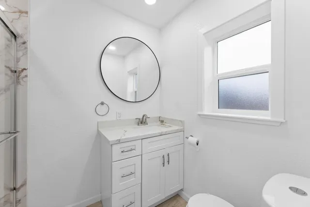 a bathroom with a toilet sink vanity and mirror