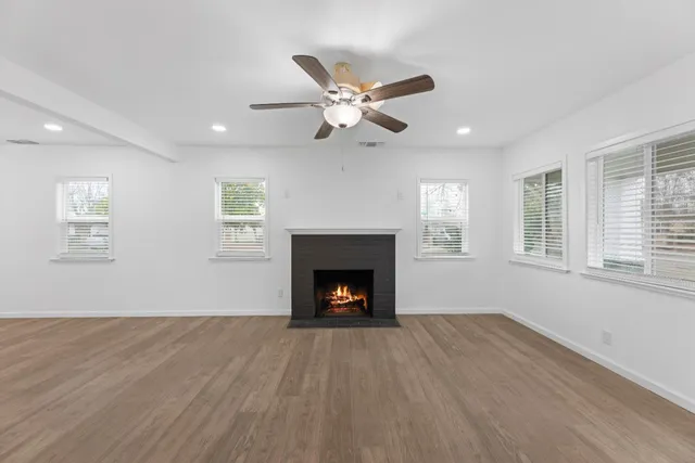 a view of an empty room with wooden floor fireplace and a window