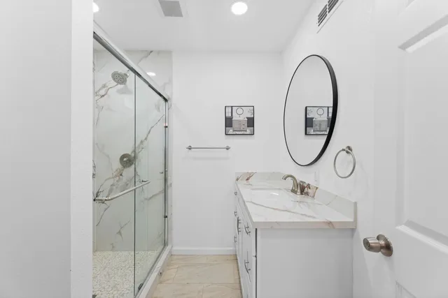 a bathroom with a sink mirror and shower