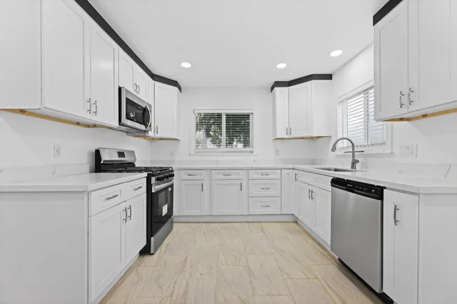 a kitchen with stainless steel appliances granite countertop a sink and dishwasher a stove top oven with white cabinets