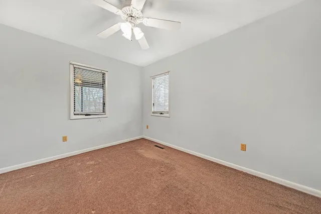 an empty room with a window and ceiling fan