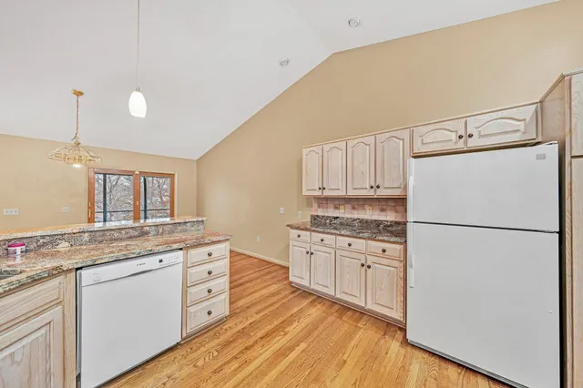 a kitchen with granite countertop cabinets appliances wooden floor and a window