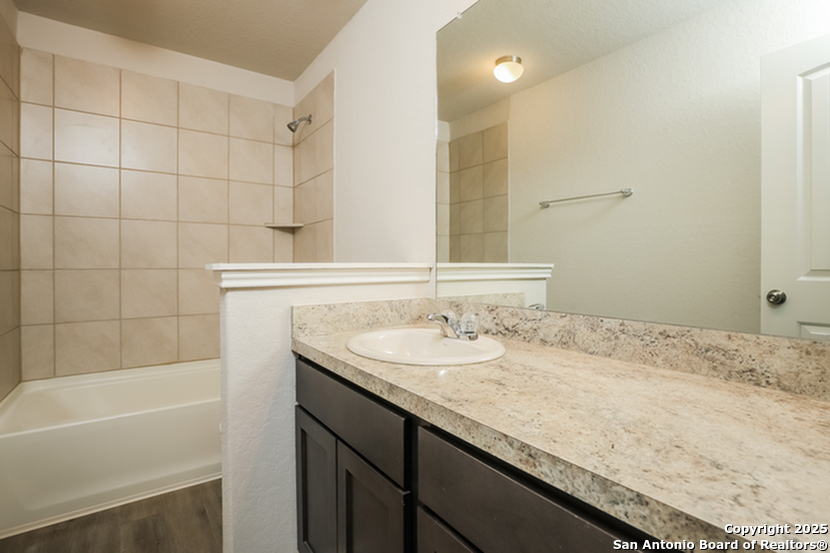 5227 Blue Ranch San Antonio, TX 78222 - Photo 13 of 17 a bathroom with a granite countertop sink a mirror and a bathtub