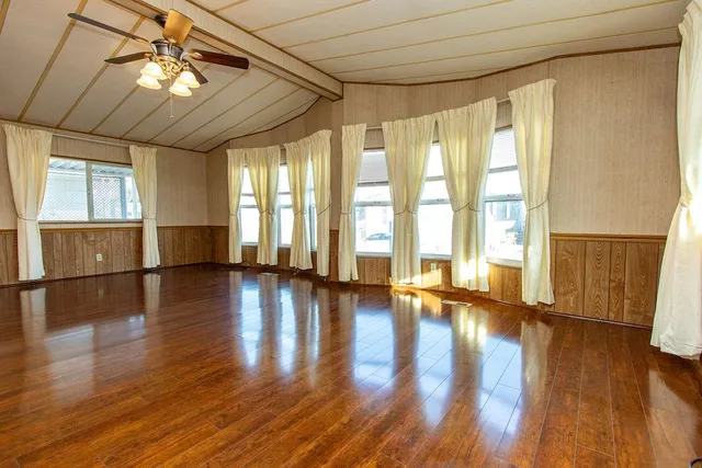 a view of empty room with wooden floor and fan